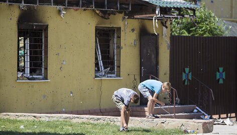 Vaikai &scaron;alia per susi&scaron;audymus nuniokoto pastato renka kulkų tūteles Luhanske.