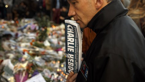 Žmogus, laikantis savaitraštį „Charlie Hebdo“ savo rankose