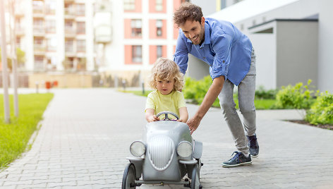 Tėtis moko sūnų vairuoti žaislinį automobilį