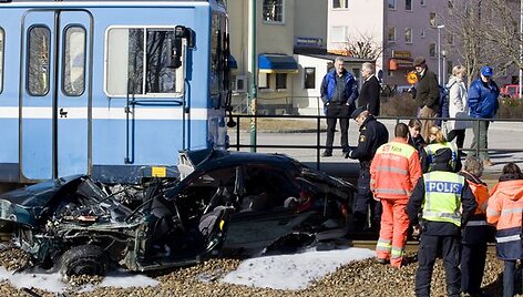 Gelbėtojai apžiūri sudaužytą automobilį.