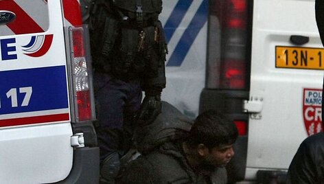 Policininkas stovi &scaron;alia suimto protestuotojo.