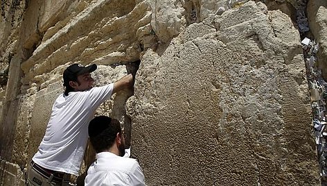 Alonas Niras (kairėje) kiša ritinėlius su maldomis į Raudų sienos plyšį