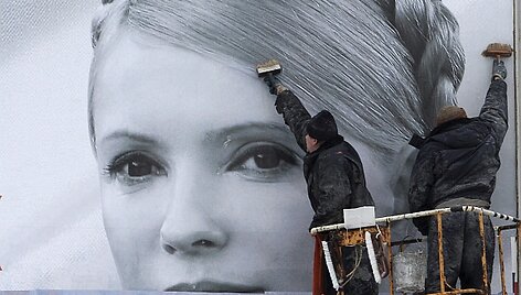 Darbininkai prie&scaron; rinkimų savaitgalį uždengia kandidatės Julijos Tymo&scaron;enko agitacinį plakatą.