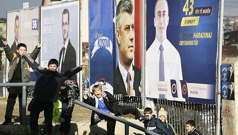 Vaikai pozuoja prie Kosove vykstančių rinkimų plakatų.