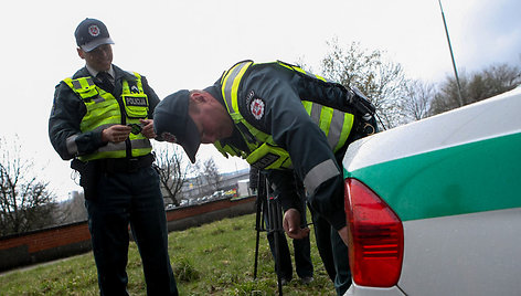 Kelių policininkas ant automobilio klijuoja lipduką „Aš neimu kyšio“