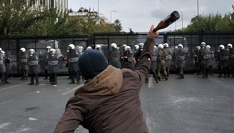 Protestuotojas meta butelį į policininkus.
