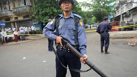 Mianmaro policininkas budi prie gaisro nuniokotos mokyklos.