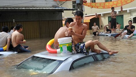 Žmonės sedi ant automobilių stogų.