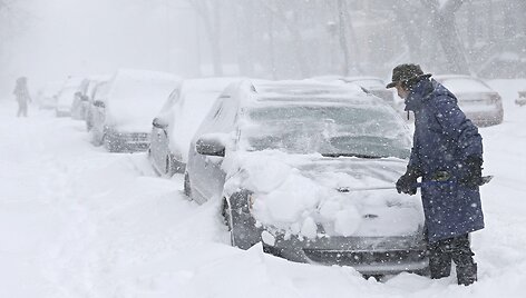 Vyras valo sniegą nuo automobilio