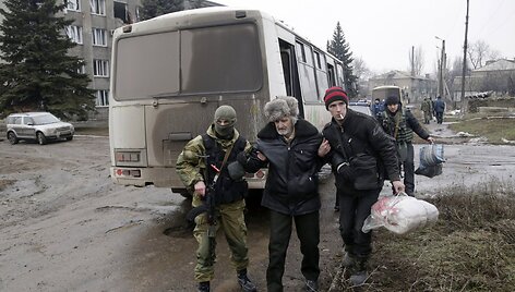 Ukrainos karys padeda vyrui pasiekti autobusą, kuriuo evakuojami gyventojai i&scaron; Debalcevės miesto.
