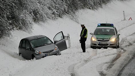 Policininkas stovi &scaron;alia nuo kelio nuslydusio automobilio