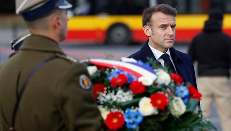 Emmanuelis Macronas lankosi prie Šarlio de Golio skulptūros Varšuvoje / WOJTEK RADWANSKI / AFP