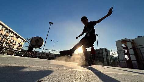 Berniukas karštą žiemą Santjage, Čilėje, žaidžia futbolą.