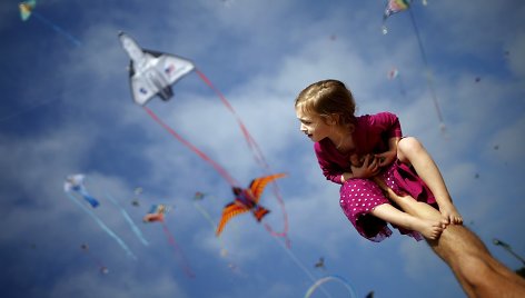 Tėtis laiko mergaitę ant rankų per aitvarų festivalį Kalifornijoje