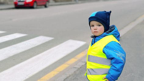 Vaikas vilki liemene su šviesą atspindinčiomis juostomis