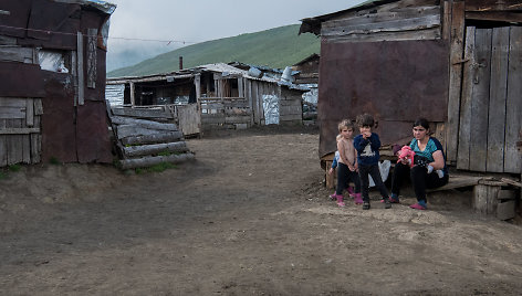 Giorgi žmona ir vaikai sėdi prie ant suoliuko prie savo namų Kaukazo kalnuose, 2022 m. Liepos 31 d. 