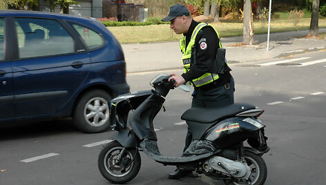 Policininkas apžiūri sudaužytą mopedą
