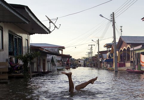Vaikas žaidžia patvinusioje Amazonės upės vandenyje Brazilijoje