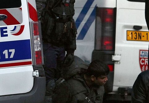 Policininkas stovi &scaron;alia suimto protestuotojo.