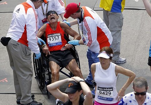 Medikai į vežimėlį sodina sunegalavusį Bostono maratono dalyvį.