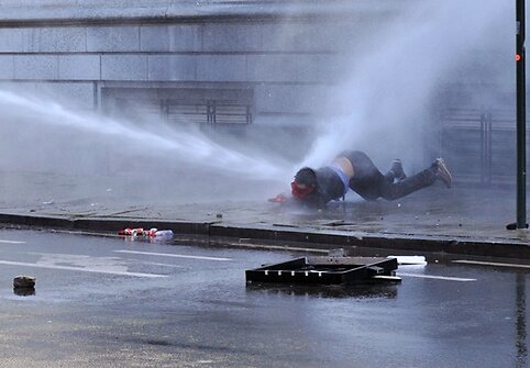 Vandens srovės parblokštas protestuotojas.