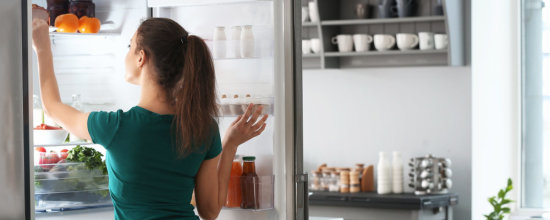 Moteris prie šaldytuvo.