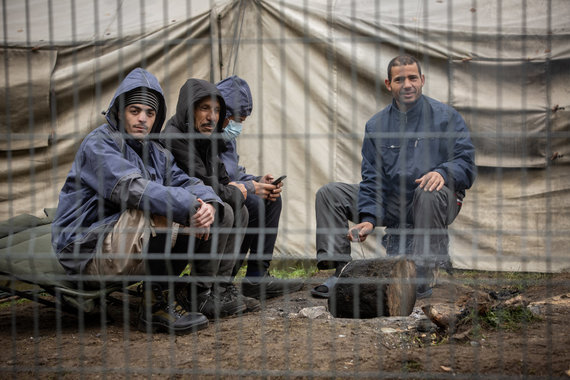 Photo by Vidmantas Balkūnas / 15-minute photo / Residents of the Rūdninkai migrant camp (Šalčininkai district) are warming themselves by the campfire.  Some of them wear new jackets and shoes donated by sheep soldiers.