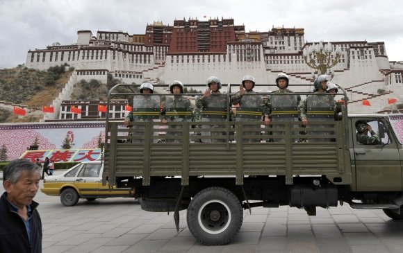 AFP/„Scanpix“ nuotr./Kinijos riaušių policija patruliuoja prie Potalos rūmų Tibeto sostinėje Lhasoje.