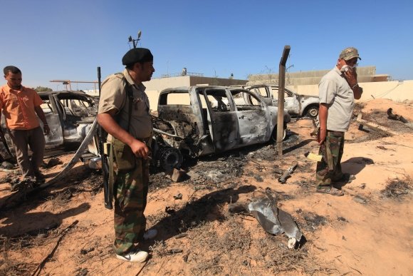 „Reuters“/„Scanpix“ nuotr./Sukilėliai prie NATO pajėgų atakuotos Muamaro Kadhafi vilkstinės automobilių