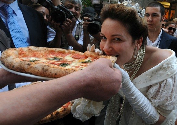 AFP/„Scanpix“ nuotr./Aktorė apsirengusi kaip karalienė ragauja picą
