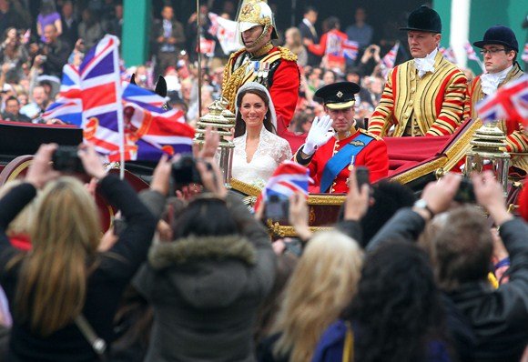 AFP/„Scanpix“ nuotr./Princas William su žmona Kate mojuoja gatvėje susirinkusiems žmonėms