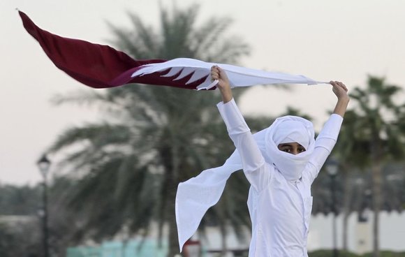 „Reuters“/„Scanpix“ nuotr./Berniukas laiko Kataro vėliavą