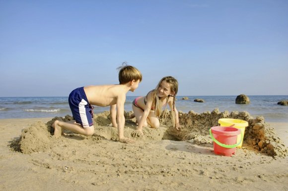 istockphoto.com nuotr./Vaikai stato smėlio pilis