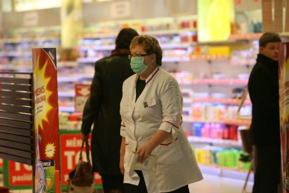 scanpix.lt nuotr./Vaistinės darbuotoja nuo siautėjančio gripo saugosi dėvėdama kaukę.