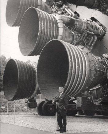 NASA nuotr./Vyriausiasis raketos „Saturn V“ architektas Wernheris von Braunas pozuoja milžiniškų pirmosios pakopos S-IC variklių F-1 fone