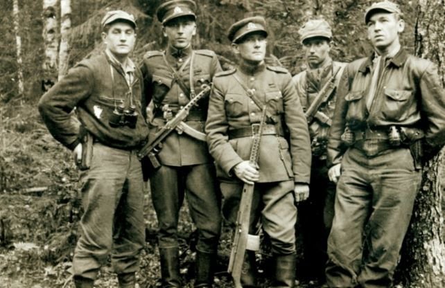Tauragės Žinios / informnapalm.org nuotr./Iš vakarų grįžę partizanai desantininkai J. Lukša (pirmas iš kairės), B. Trumpys (ketvirtas) ir K. Širvys (penktas) susitikime su Tauro apygardos vadu V. Vitkausku (antras iš kairės) ir vado adjutantu P. Naujoku (1949 m.)