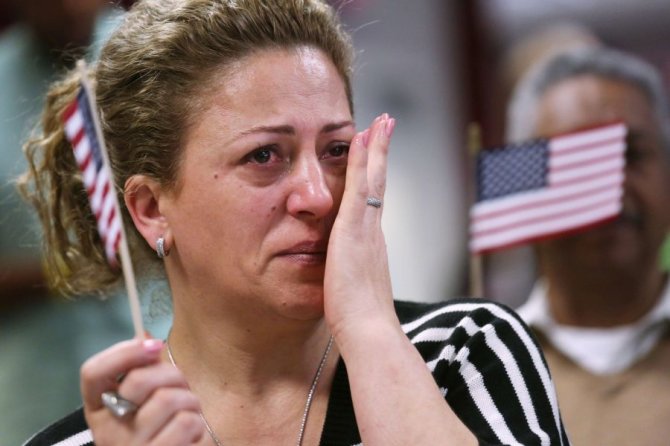 AFP/Scanpix nuotr./Neseniai JAV pilietybę gavusi moteris braukia džiaugsmo ašarą. 