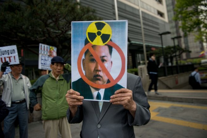 AFP/„Scanpix“ nuotr./Protestuotojas Seule laiko plakatą su Šiaurės Korėjos lyderio Kim Jong Uno atvaizdu