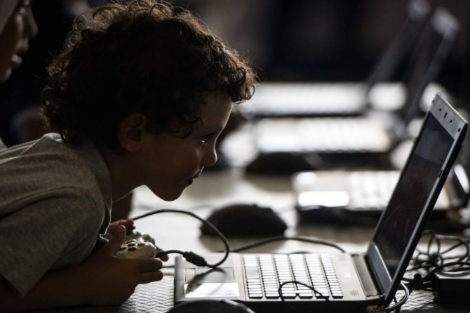 AFP/„Scanpix“ nuotr./Vaikas žaidžia su kompiuteriu