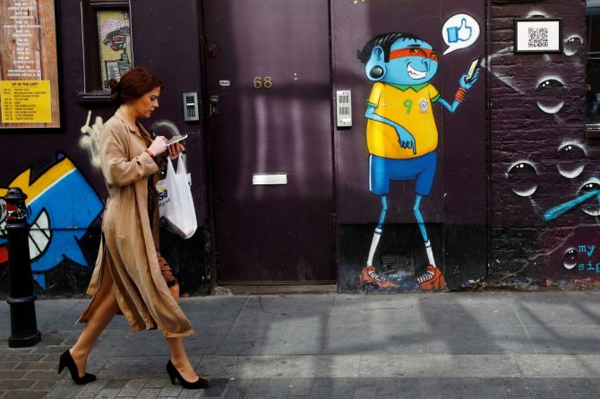 „Reuters“/„Scanpix“ nuotr./Telefonų ekranai užvaldę Londono gyventojus