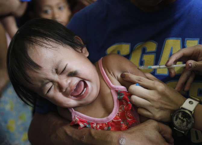 „Reuters“/„Scanpix“ nuotr./Vaikui švirkščiama vakcina nuo tymų