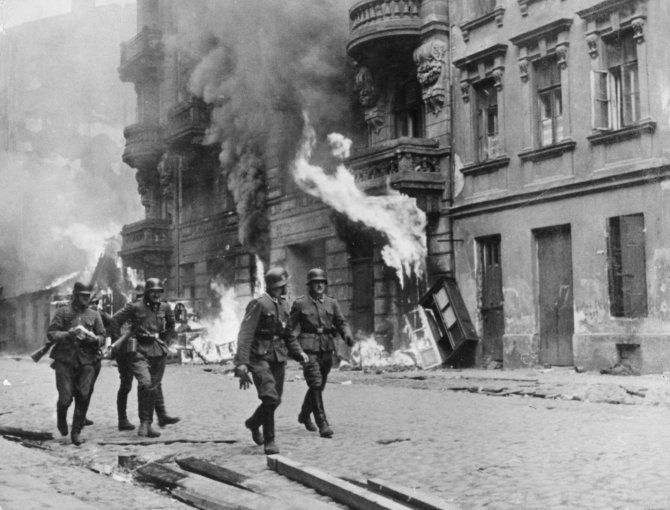 Vida Press nuotr./Vokiečių kareiviai 1943 m. eina pro padegtą Varšuvos getą, kuris po sukilimo buvo sudegintas iki pamatų 