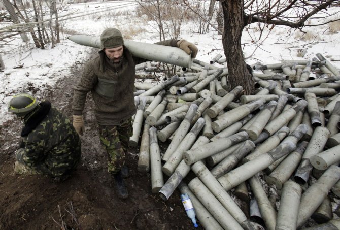 AFP/„Scanpix“ nuotr./Ukrainos karys eina šalia krūvos panaudotų artilerijos sviedinių tūtų.