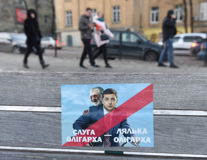 AFP/„Scanpix“ nuotr./Plakatas su užrašu „Oligarcho tarnas“. Ant jo – Ihoris Kolomoiskis ir Volodymyras Zelenskis