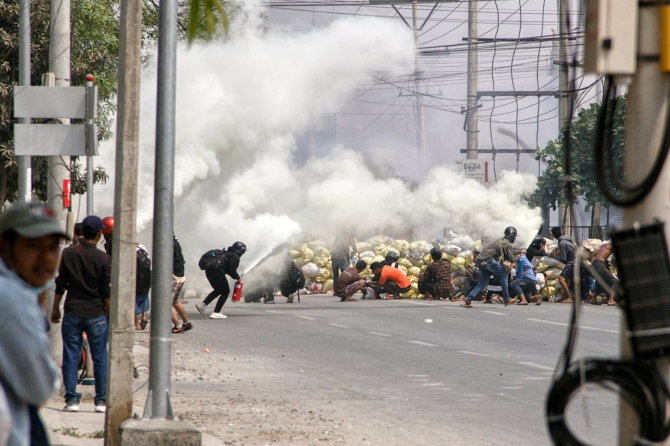 „Reuters“/„Scanpix“ nuotr./Mianmaro protestuotojai slepiasi už barikadų.