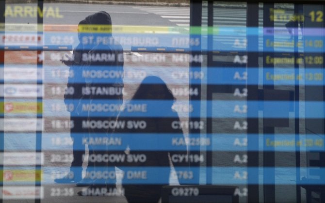 „Reuters“/„Scanpix“ nuotr./Žmonės atsispindi Kazano oro uosto informaciniame ekrane / Maxim Shemetov / REUTERS
