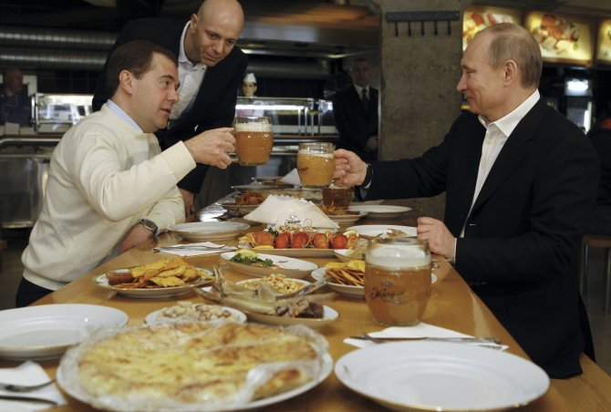 „Reuters“/„Scanpix“ nuotr./Dmitrijus Medvedevas ir Vladimiras Putinas prie vaišių stalo