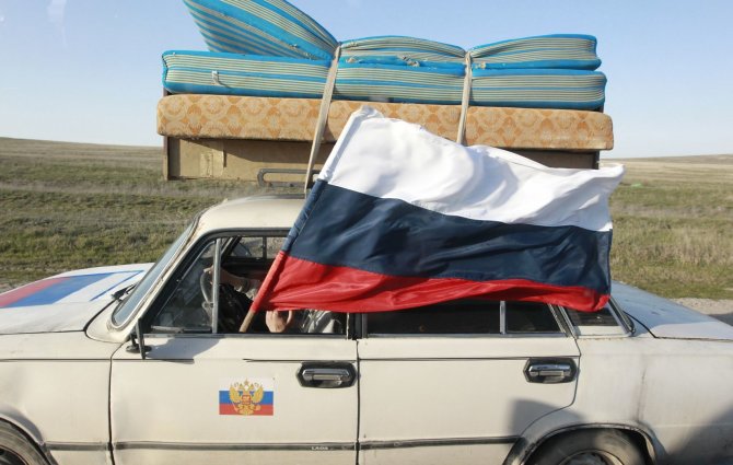 „Reuters“/„Scanpix“ nuotr./Per automobilio langą iškišta Rusijos vėliava 