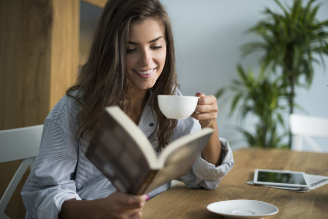 123RF.com nuotr./Mergina geria kavą ir skaito knygą