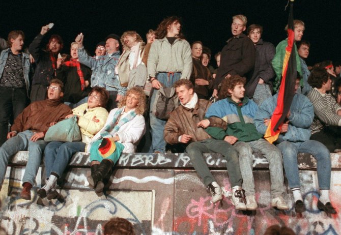 „Scanpix“/„Picture-Alliance“ nuotr./Žmonės dainuoja užlipę ant Berlyno sienos (1989 m.)